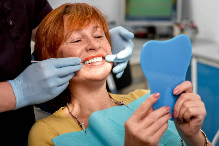 Dentiste ou Denturiste, Denturologue 1 Patiente avec des nouvelles prothèses. Avancée sociale. chez le denturiste ou le dentiste